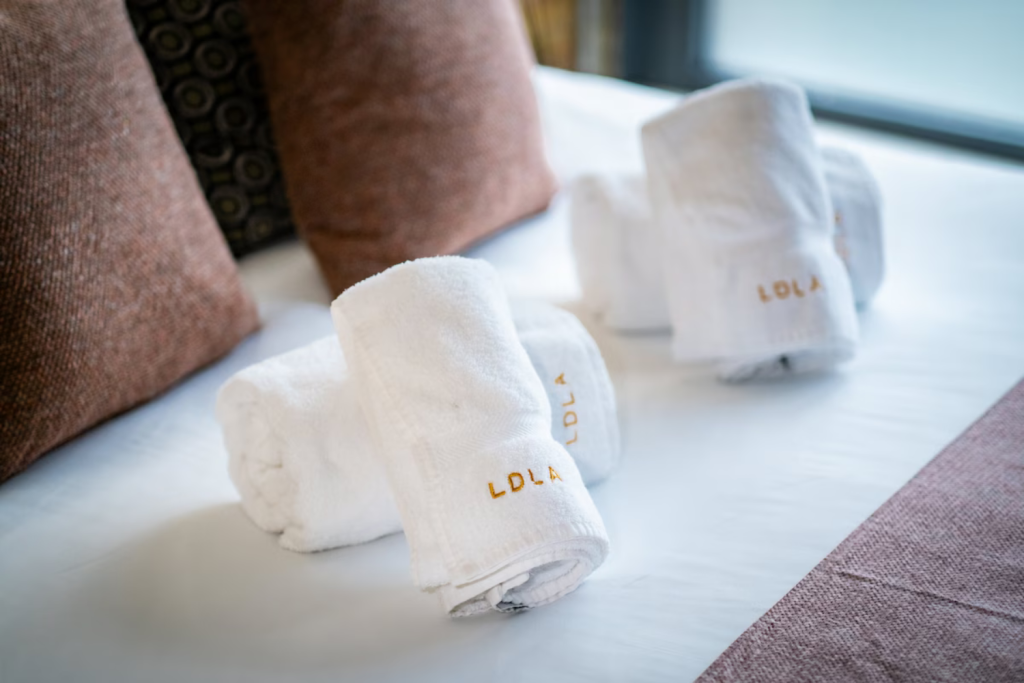 12 towels rolled on a bed